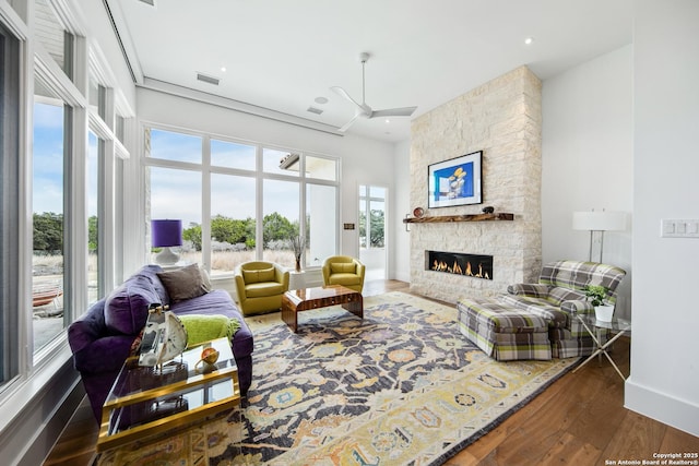 living room with a stone fireplace, recessed lighting, wood finished floors, visible vents, and baseboards