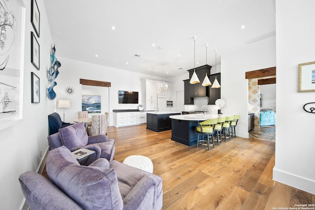 living room featuring light wood-type flooring, baseboards, and recessed lighting