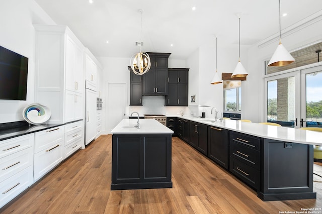 kitchen with light countertops, dark cabinetry, a peninsula, and hardwood / wood-style flooring