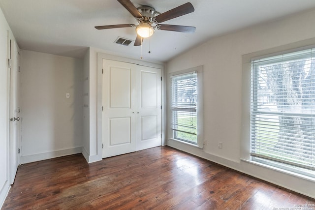 unfurnished bedroom with dark wood-type flooring, a closet, visible vents, and baseboards