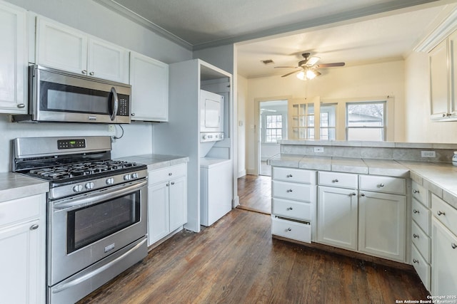 kitchen with stacked washer and dryer, appliances with stainless steel finishes, white cabinets, and light countertops