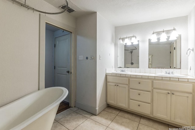 bathroom featuring visible vents, a sink, a freestanding bath, and tile patterned floors