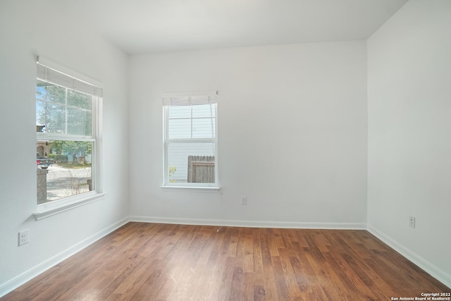 spare room featuring dark wood-style flooring, a wealth of natural light, and baseboards