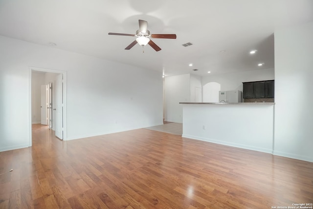 unfurnished living room with arched walkways, recessed lighting, visible vents, a ceiling fan, and light wood finished floors