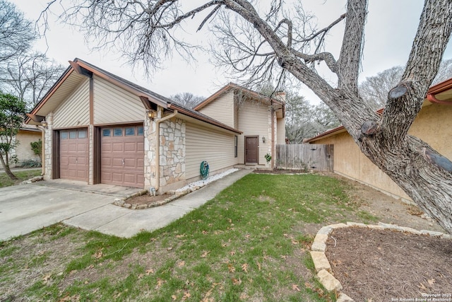 view of side of home featuring a garage, stone siding, a lawn, and fence