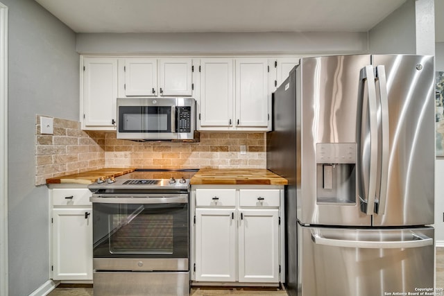 kitchen featuring white cabinets, wood counters, stainless steel appliances, and backsplash