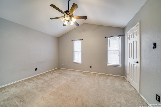 spare room with lofted ceiling, baseboards, a ceiling fan, and light colored carpet