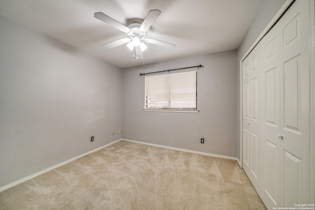 unfurnished bedroom featuring a ceiling fan, a closet, light carpet, and baseboards