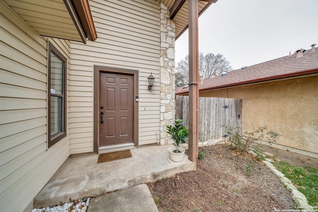 doorway to property with stone siding and fence