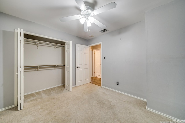 unfurnished bedroom featuring baseboards, visible vents, light colored carpet, ceiling fan, and a closet