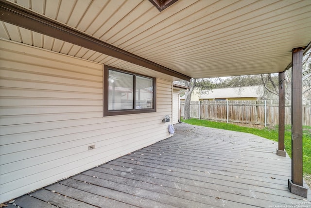 wooden terrace featuring a carport and fence