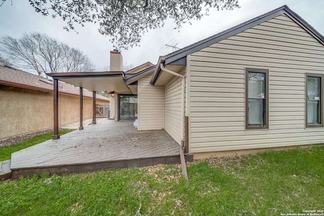 rear view of property with a lawn, a chimney, and a wooden deck