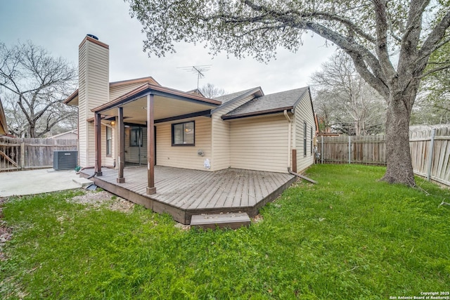 rear view of property with a yard, a chimney, a deck, cooling unit, and a fenced backyard