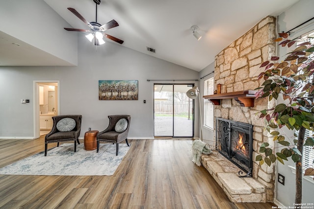 living area with a fireplace, visible vents, a ceiling fan, wood finished floors, and baseboards