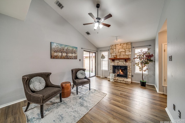 living area with a stone fireplace, wood finished floors, and visible vents