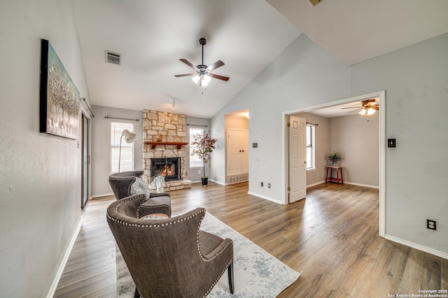 living area with a fireplace, wood finished floors, visible vents, baseboards, and a ceiling fan