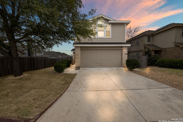 traditional home featuring a garage, fence, concrete driveway, and brick siding