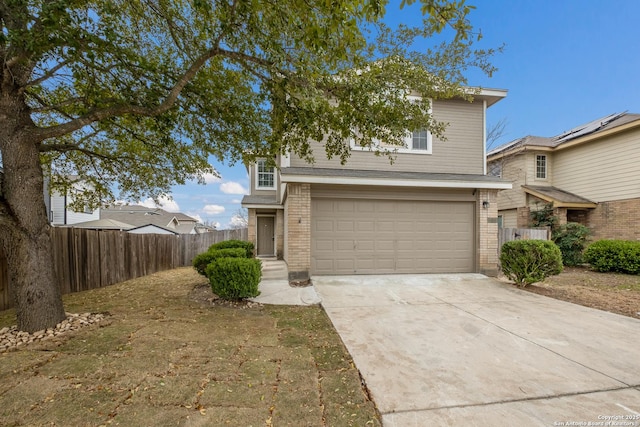 traditional-style house with concrete driveway, brick siding, fence, and an attached garage