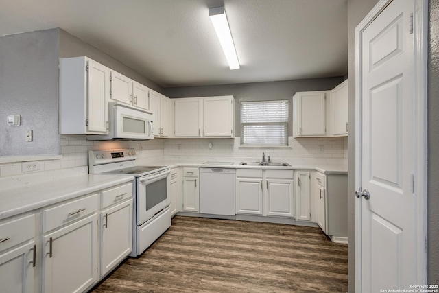 kitchen featuring white appliances, white cabinets, dark wood-style flooring, light countertops, and a sink