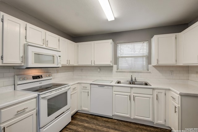 kitchen with light countertops, dark wood-type flooring, white cabinets, a sink, and white appliances