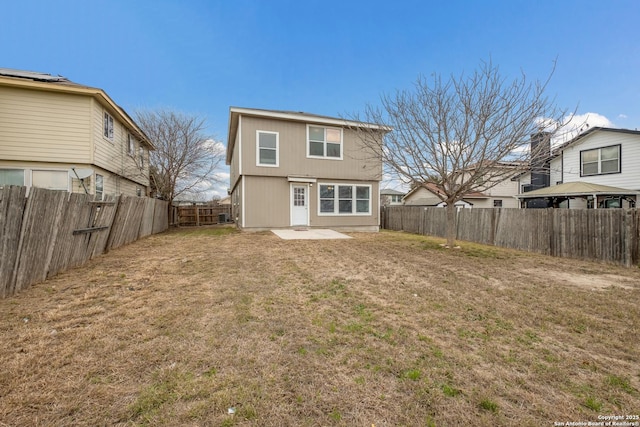 rear view of house featuring a lawn, a patio area, and a fenced backyard