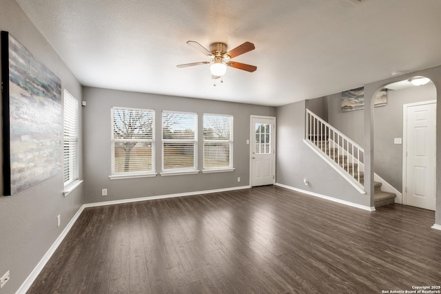 interior space featuring stairs, ceiling fan, dark wood-style flooring, and plenty of natural light