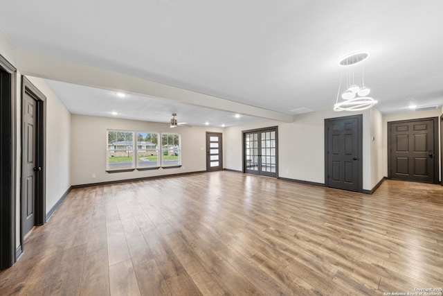 unfurnished living room with light wood-style flooring, baseboards, and an inviting chandelier