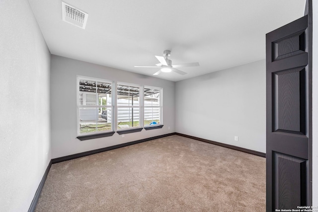 carpeted spare room featuring visible vents, ceiling fan, and baseboards