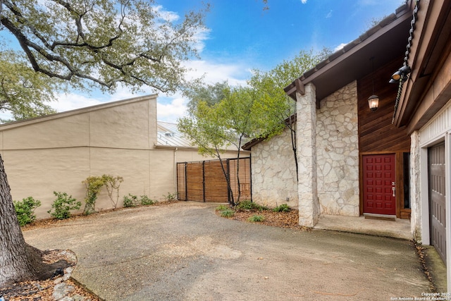 view of side of home with metal roof, stone siding, and fence