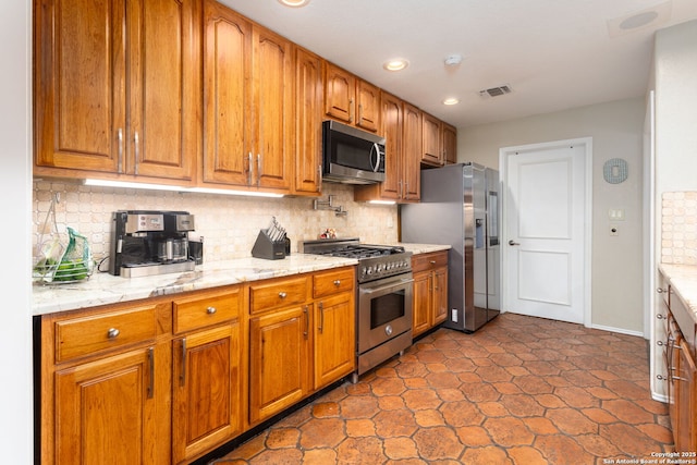 kitchen featuring brown cabinets, stainless steel appliances, tasteful backsplash, visible vents, and light stone countertops