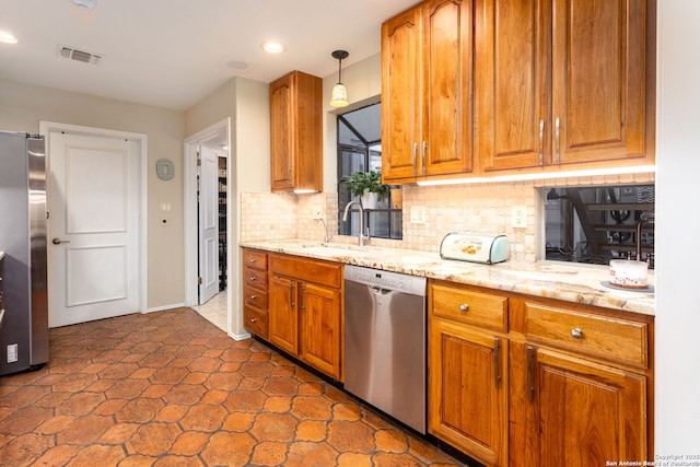 kitchen with a sink, visible vents, appliances with stainless steel finishes, backsplash, and pendant lighting