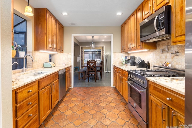 kitchen featuring stainless steel appliances, brown cabinets, a sink, and pendant lighting