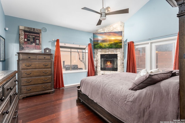 bedroom featuring lofted ceiling, dark wood-style floors, ceiling fan, and a stone fireplace