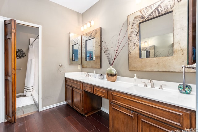 bathroom with double vanity, a sink, baseboards, and wood finished floors