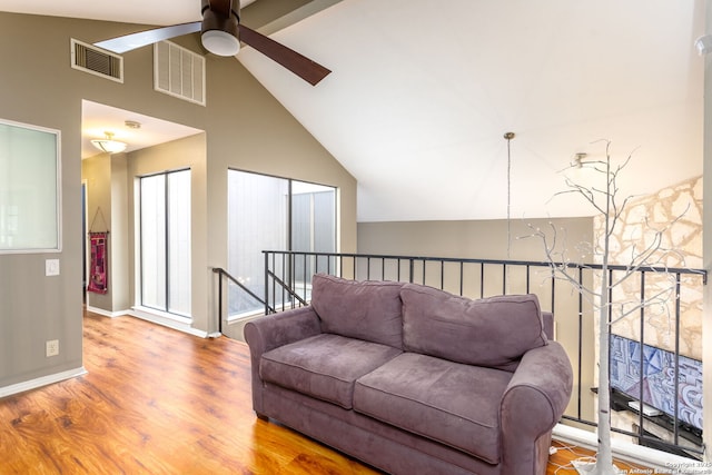 living area featuring lofted ceiling with beams, baseboards, visible vents, and wood finished floors