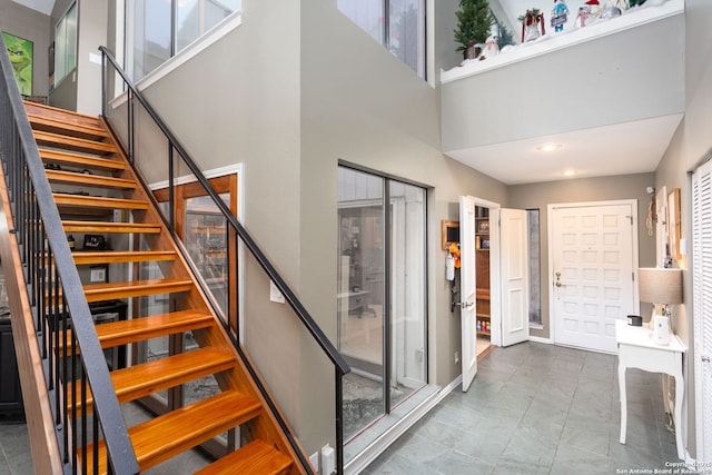 foyer entrance with plenty of natural light, a towering ceiling, and stairs