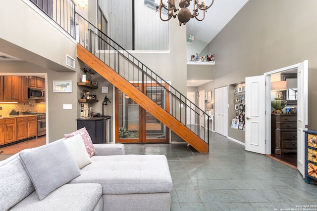 living room with stairs, a high ceiling, a chandelier, and visible vents