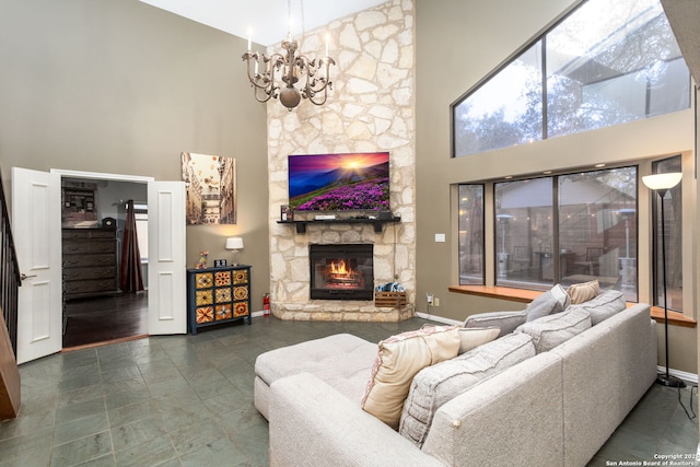 living room with a high ceiling, baseboards, a notable chandelier, and a stone fireplace