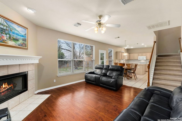 living room featuring light wood-style flooring, visible vents, and a tile fireplace