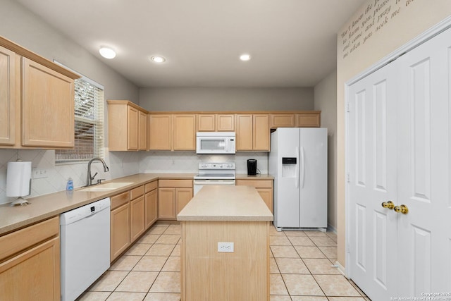 kitchen with white appliances, light brown cabinets, a kitchen island, and light countertops