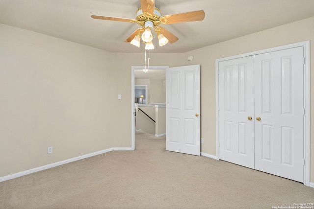 unfurnished bedroom with light carpet, a closet, a ceiling fan, and baseboards