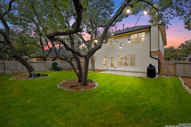 back of house with a fenced backyard, a yard, and a patio