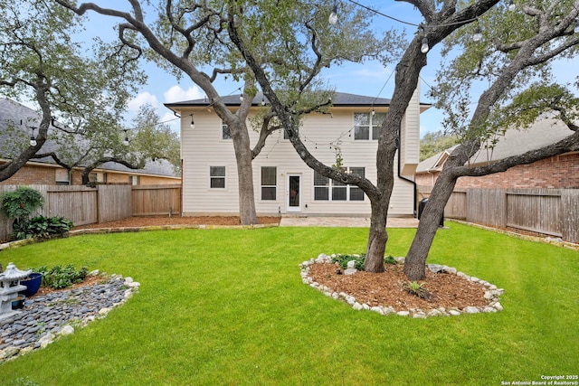 rear view of house featuring a fenced backyard and a lawn