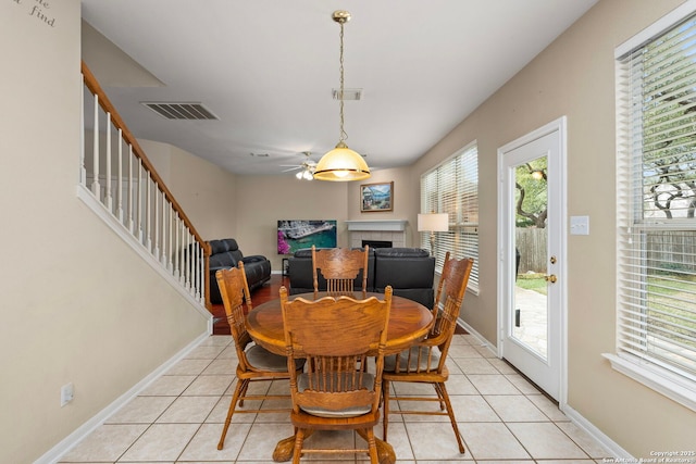 dining area with light tile patterned floors, a fireplace, stairs, and visible vents