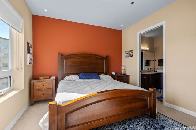 bedroom with ensuite bathroom, a sink, and baseboards