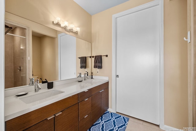 full bath featuring double vanity, tiled shower, tile patterned flooring, and a sink