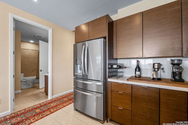 kitchen with light tile patterned floors, light countertops, baseboards, and stainless steel fridge with ice dispenser