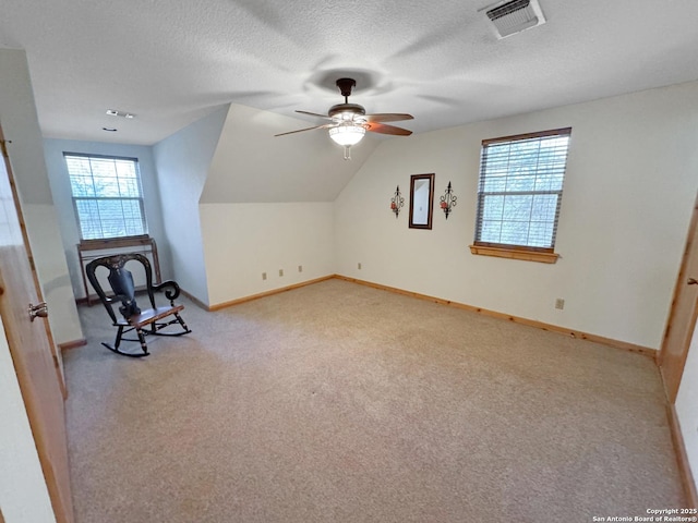 interior space featuring lofted ceiling, visible vents, a textured ceiling, and light colored carpet