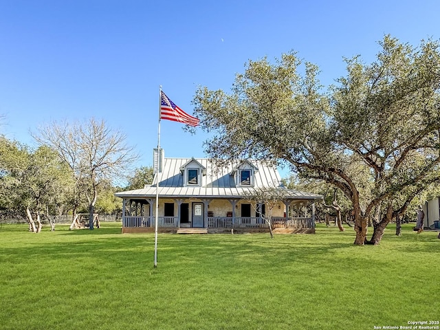 rear view of house featuring a lawn, a chimney, metal roof, a standing seam roof, and covered porch