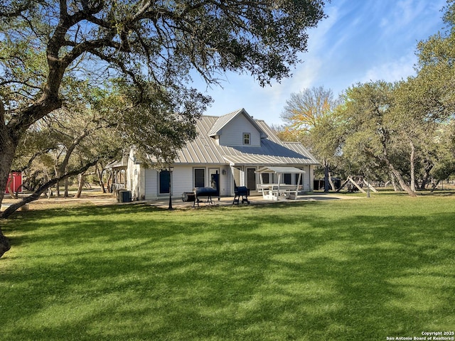 rear view of house with a lawn, metal roof, central AC, and a patio